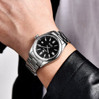 Silver watch with black dial on a wrist against a neutral background